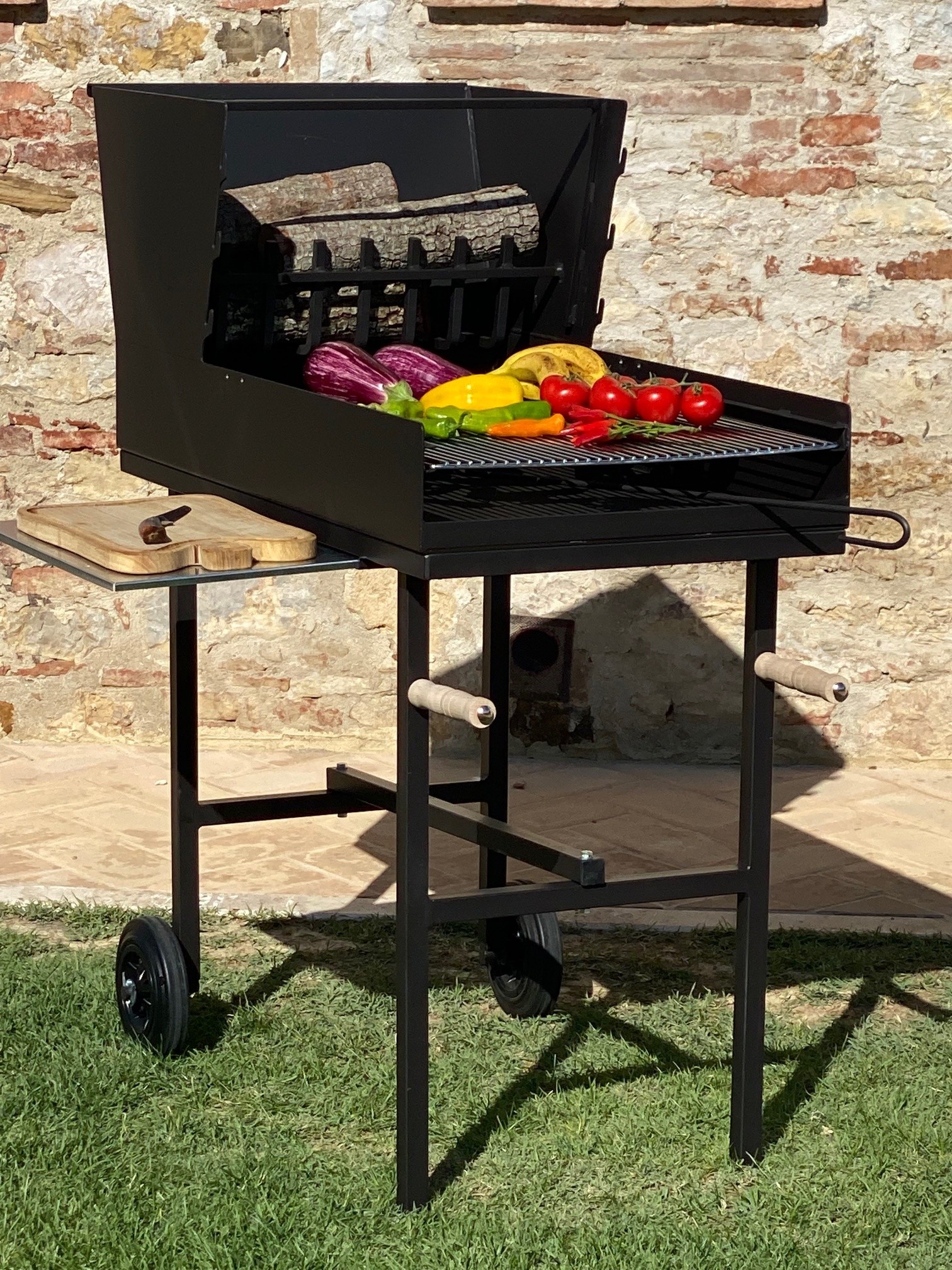 Assado Rotisserie BBQ Article No. 030.0006 at the house wall with vegetables uncooked on the grill rack and with cutting board